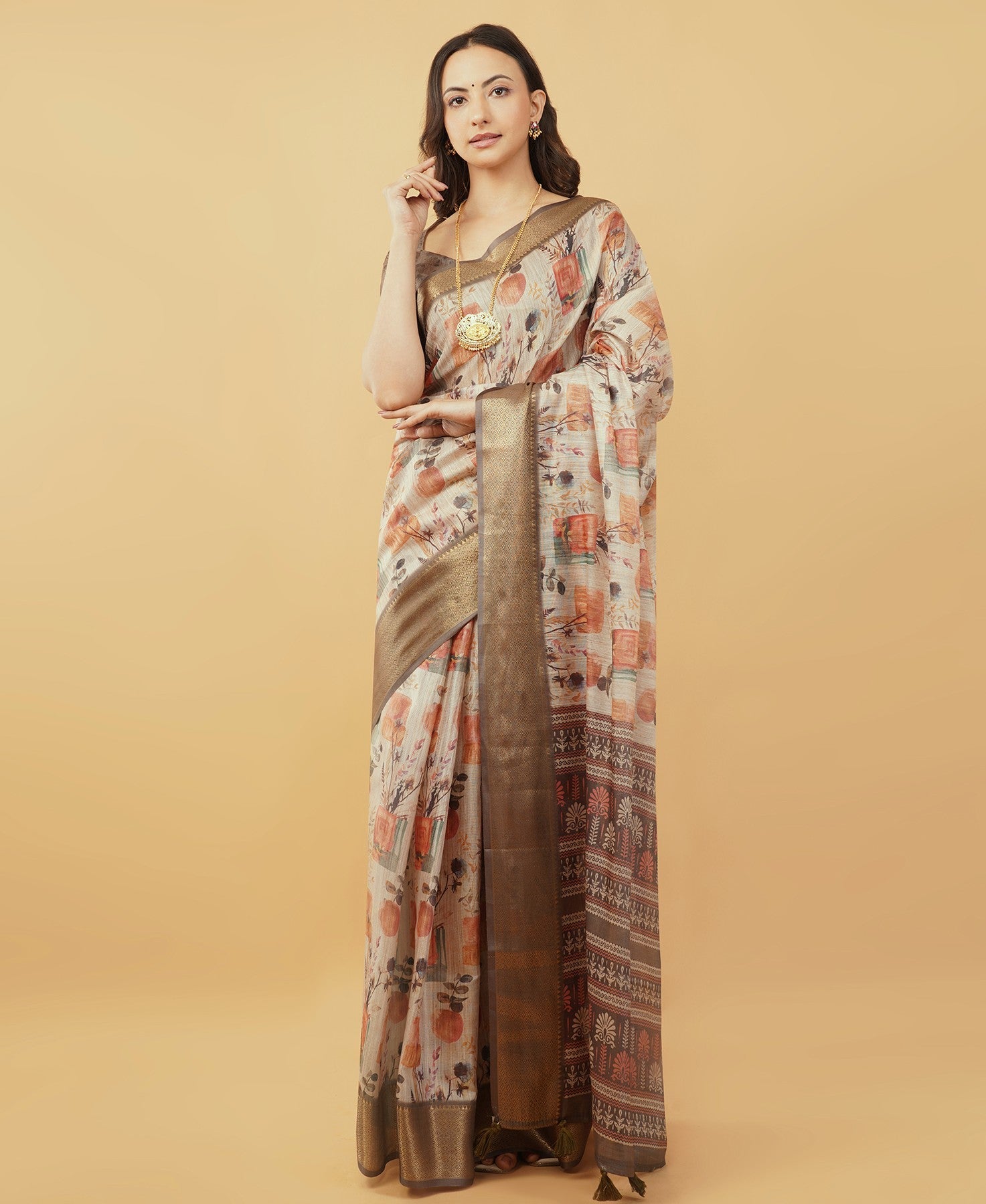 Cream and rust botanical print saree with bronze zari border and tassel pallu