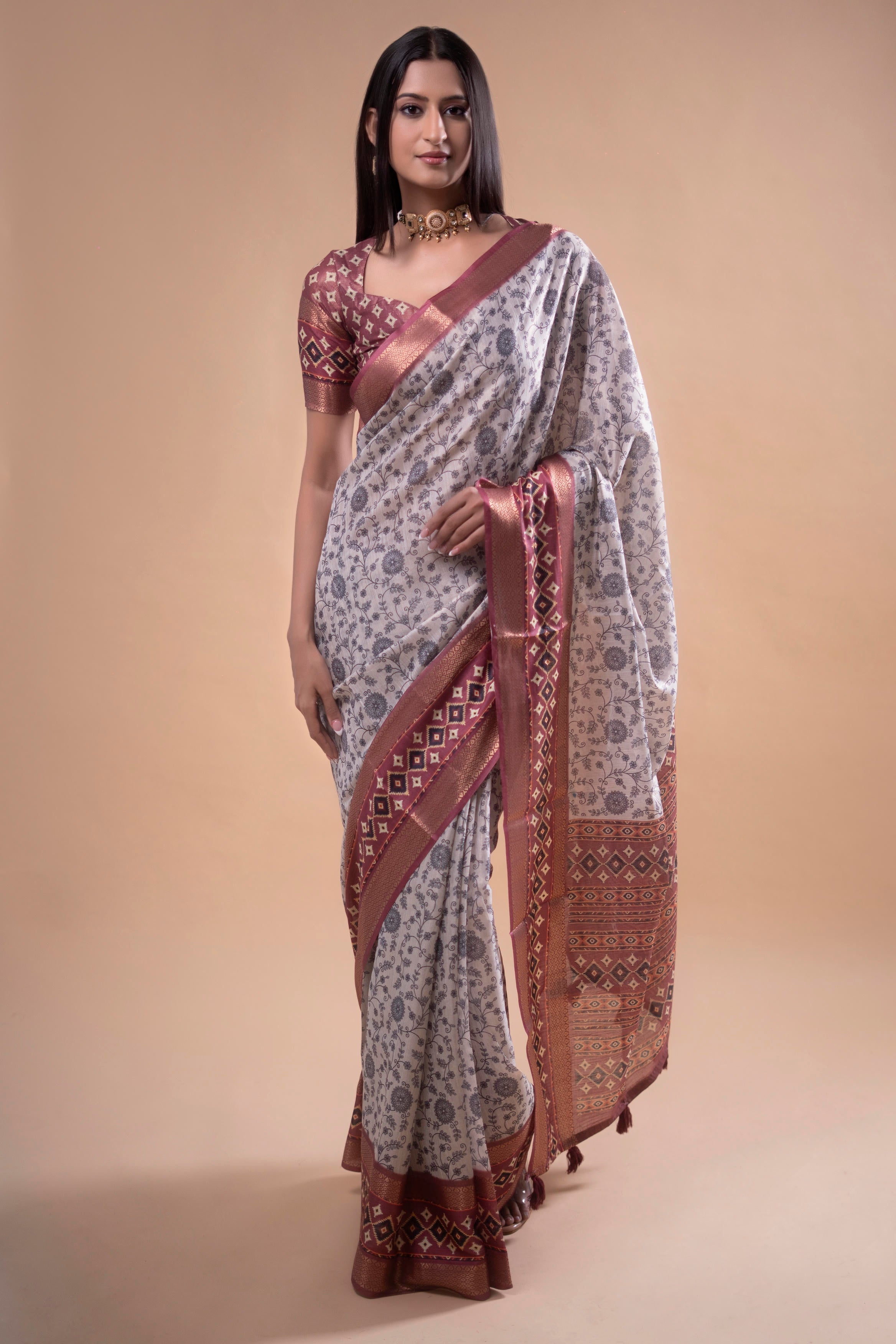 Cream floral saree with maroon geometric zari border and tassel pallu
